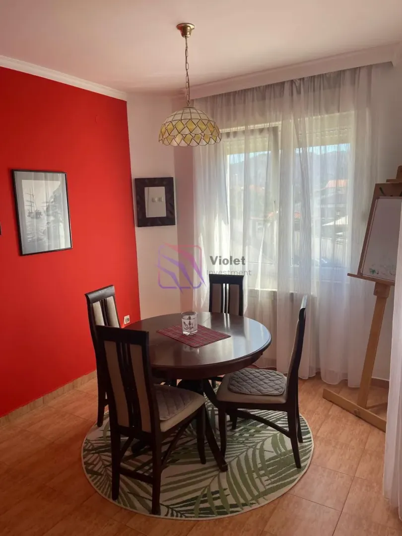 Dining table with chairs in a living room with a red wall.