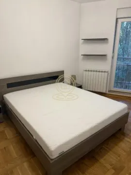 Spavaća soba sa bračnim krevetom i parketom na podu. - image 4