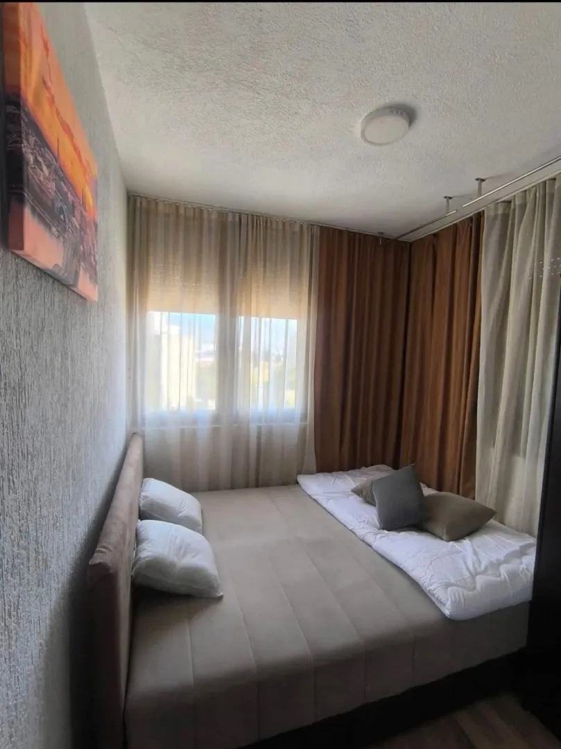 Small bedroom with a double bed and curtained windows.