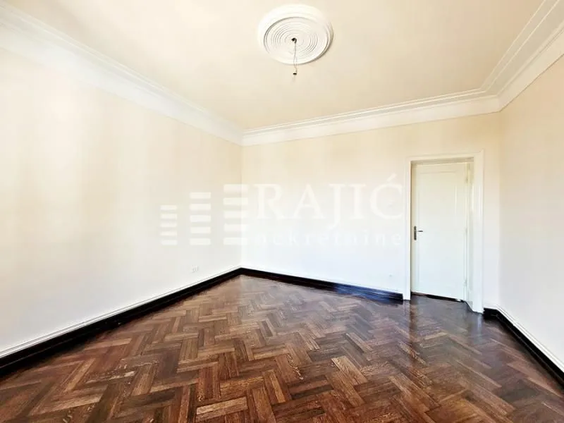 Empty room with parquet flooring and white walls.