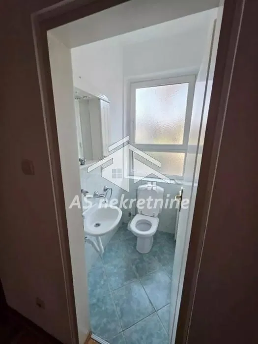 Pogled na kupatilo sa umivaonikom i wc šoljom kroz vrata.