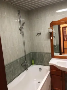 Bathroom with a bathtub and wooden vanity with a mirror. - image 9