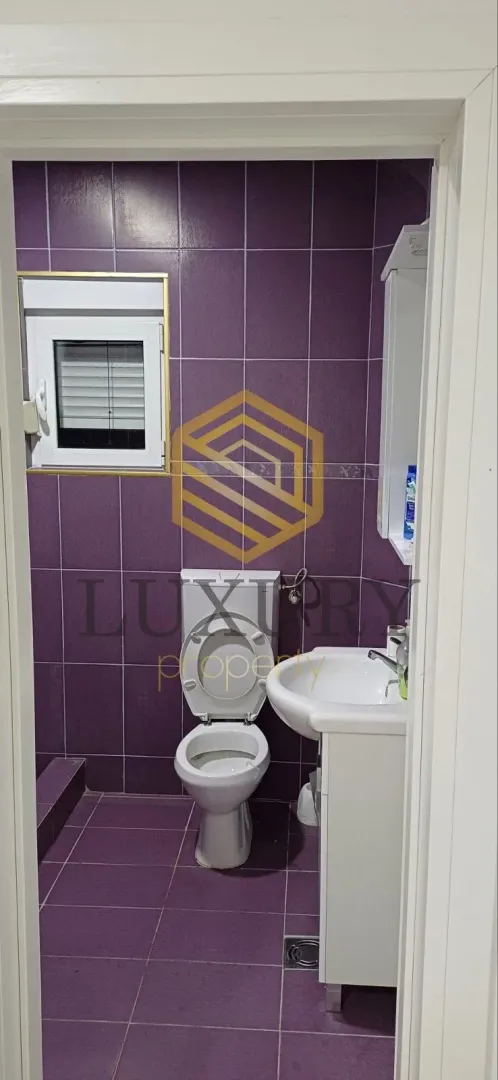 Small bathroom with purple tiles and sanitaryware.