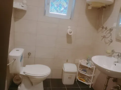 Manje kupatilo obloženo keramičkim pločicama sa toaletom i umivaonikom. - image 4