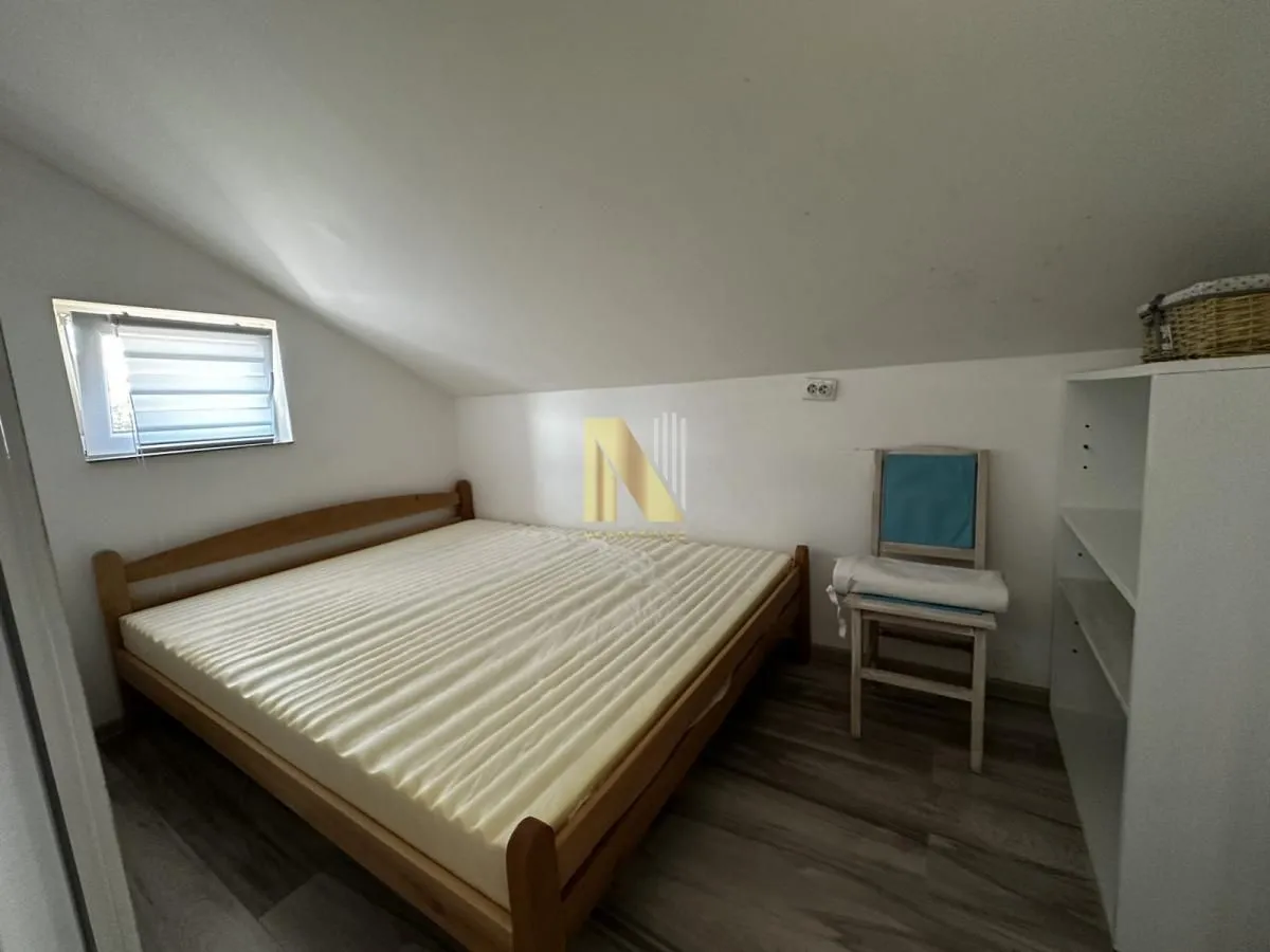 Manja spavaća soba sa bračnim krevetom pod kosim krovom.