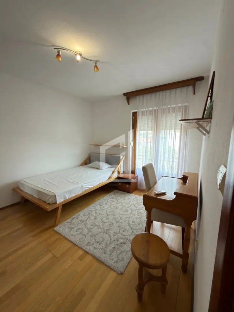 Bedroom with a single bed, desk, and hardwood flooring.