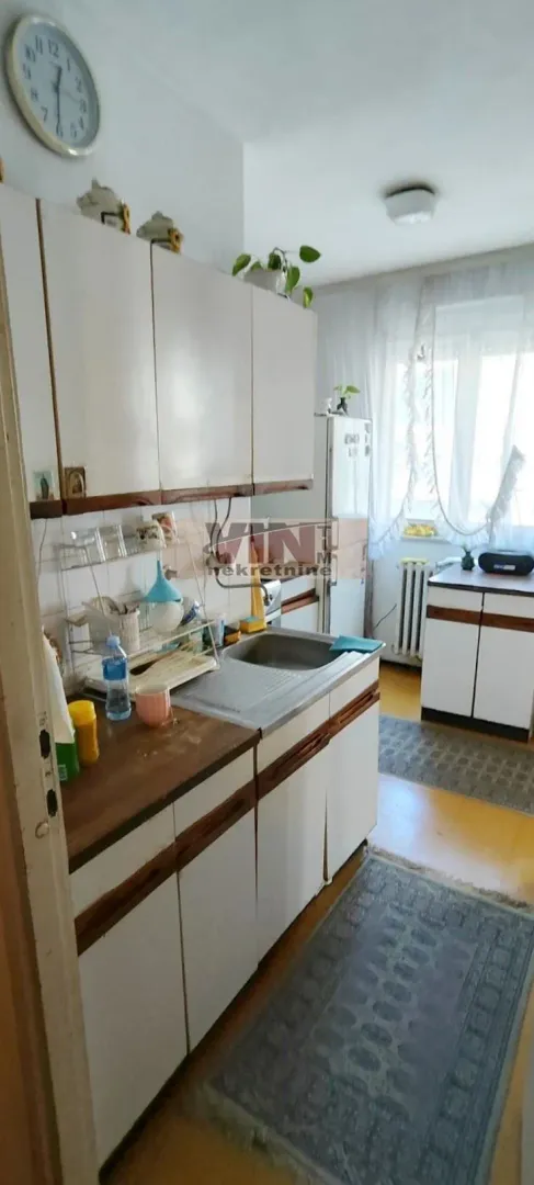 Starija kuhinja sa belim elementima i sudoperom.