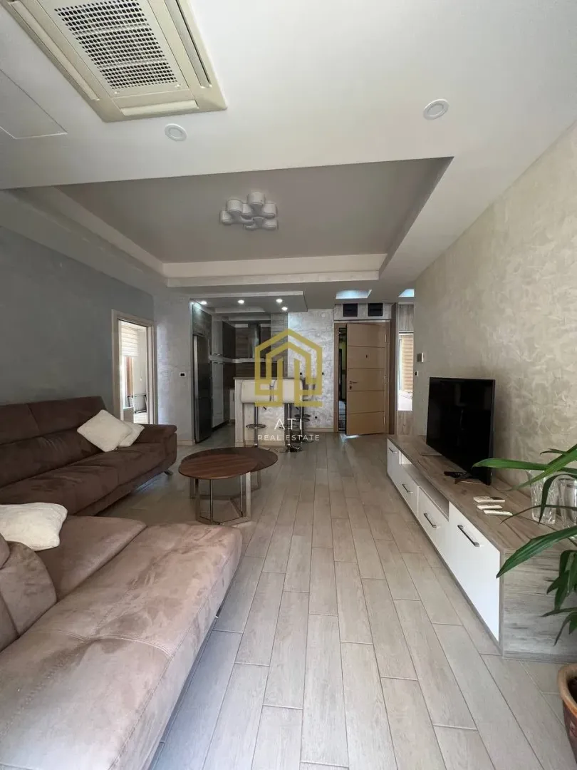 Spacious living room with a sofa, TV, and dining area in the background.