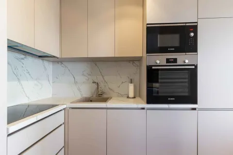 Moderna kuhinja sa ugrađenim aparatima i mermernom radnom površinom. - image 5