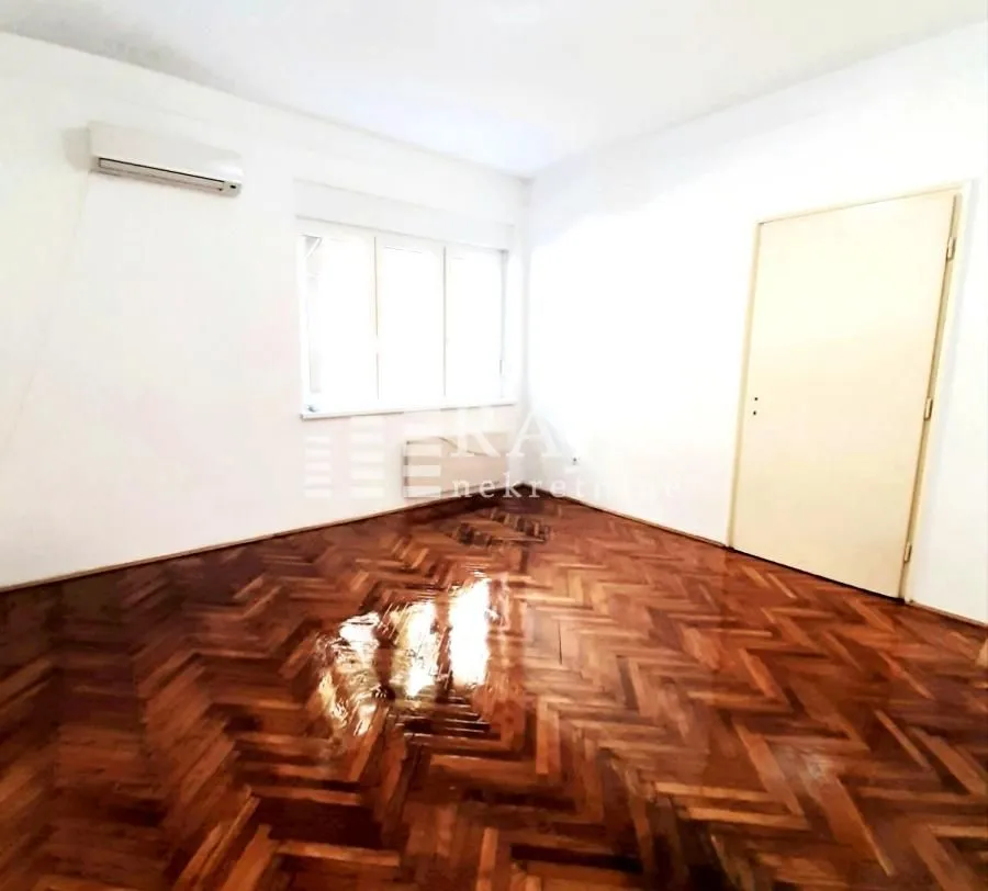 Empty room with parquet flooring and an air conditioner.