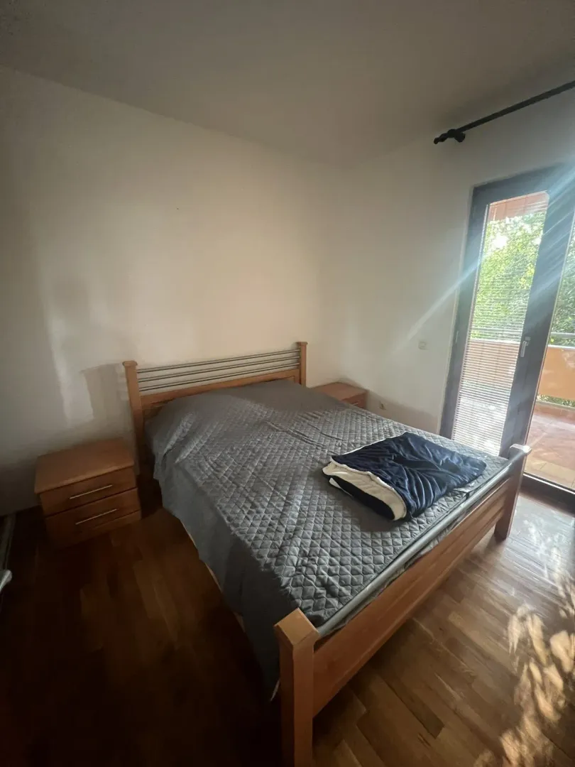 Simple bedroom with a wooden double bed and access to a terrace.
