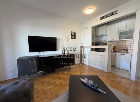 Living room with a sofa and TV connected to the kitchen. - image 3