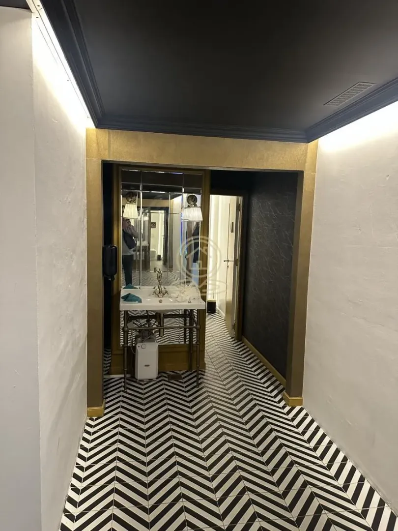 Small bathroom with a washbasin, mirror and black and white floor tiles.