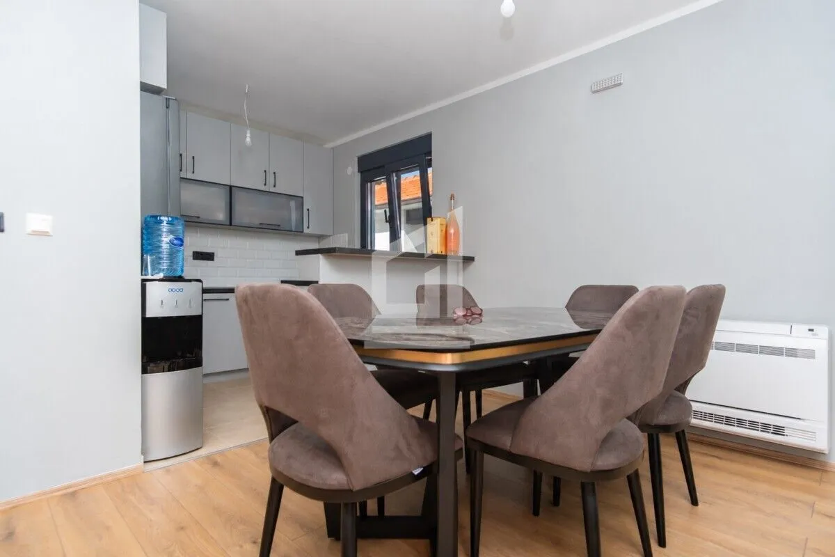 Dining area with a table and chairs, with a view of the kitchen in the background.