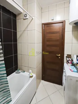 Bathroom with a bathtub, wooden door and washing machine. - image 8