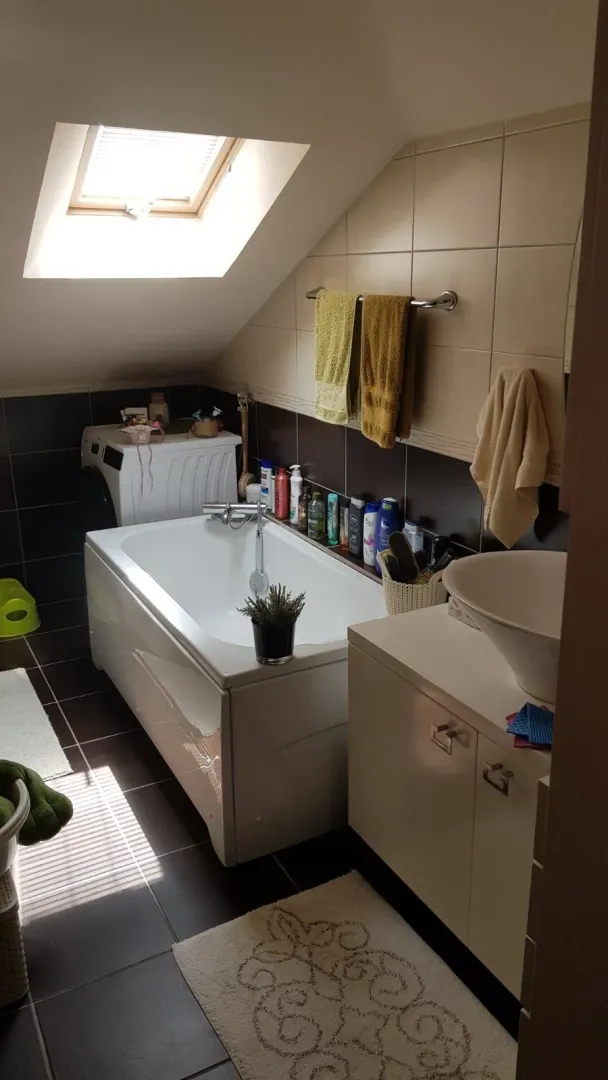 Kupatilo u potkrovlju sa kadom, umivaonikom i krovnim prozorom.
