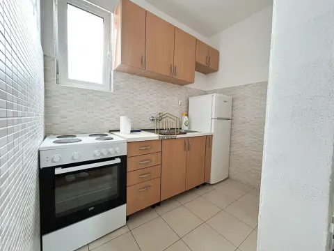 Manja kuhinja sa drvenim elementima, šporetom i frižiderom. - image 2