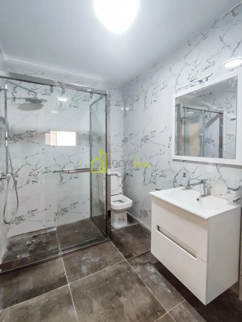 Modern bathroom with a walk-in shower, vanity, and toilet.