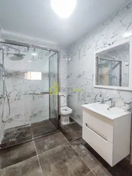 Modern bathroom with a walk-in shower, vanity, and toilet. - image 9
