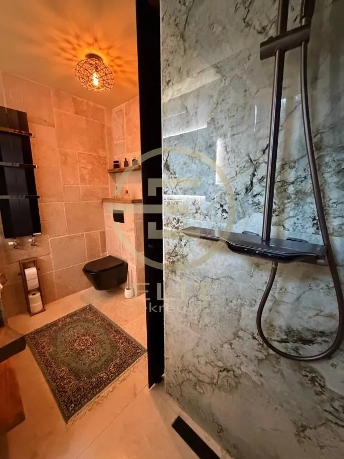 Moderno kupatilo sa tuš kabinom i WC šoljom.