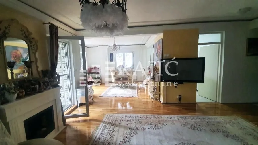 Spacious living room with a fireplace, hardwood floors, and a dining area in the background.
