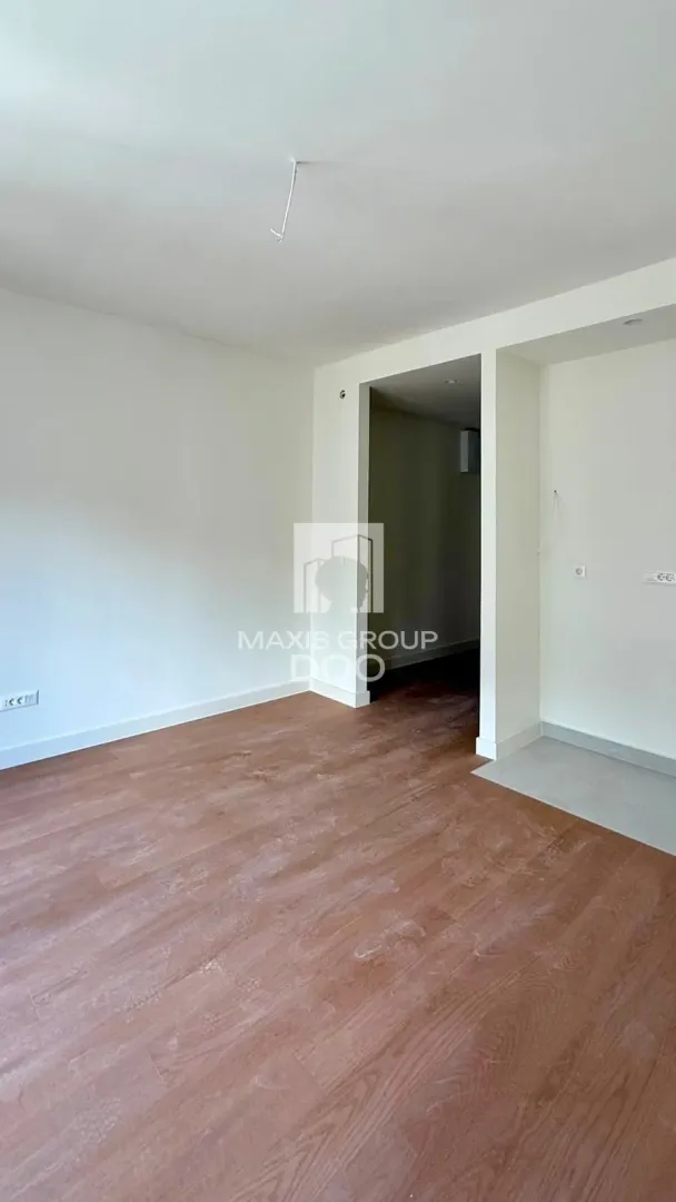 Empty room with wooden flooring and white walls.