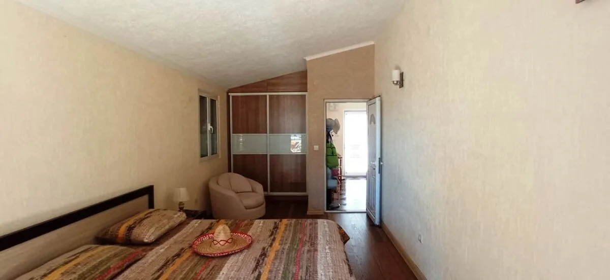 Furnished bedroom with a double bed, wardrobe, and an armchair.