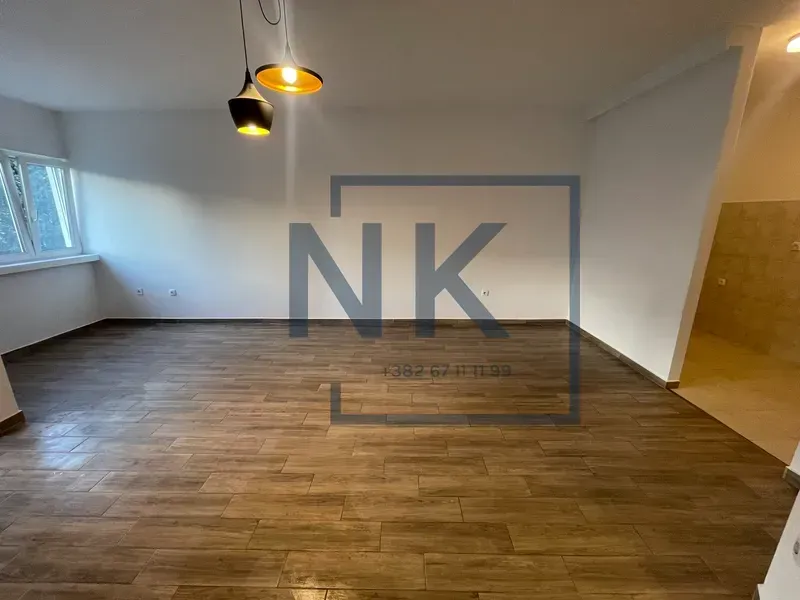 Empty room with wooden flooring and pendant lights.