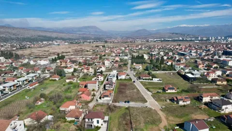 Pogled iz vazduha na naselje sa porodičnim kućama i planinama u pozadini. - image 4
