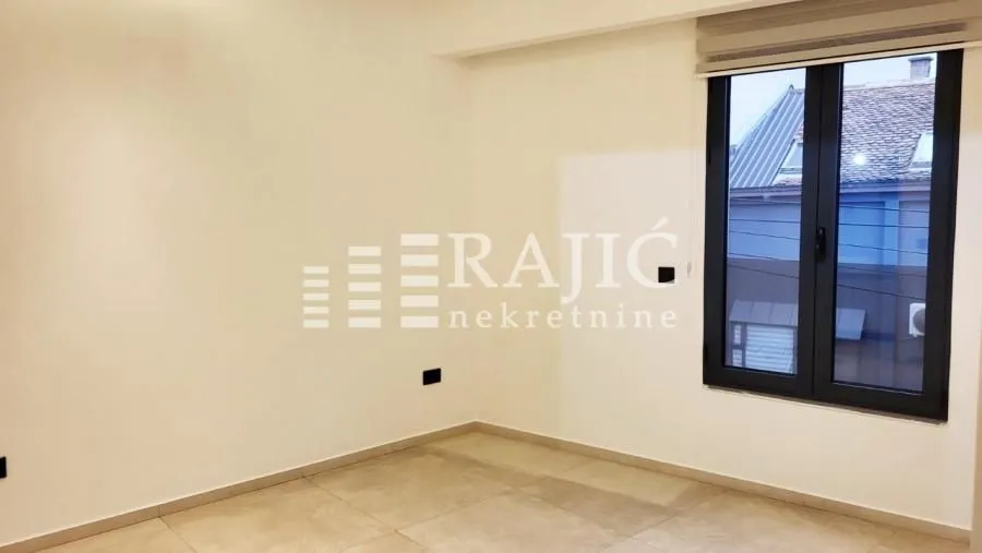 Empty bright room with a window and tiled floor.