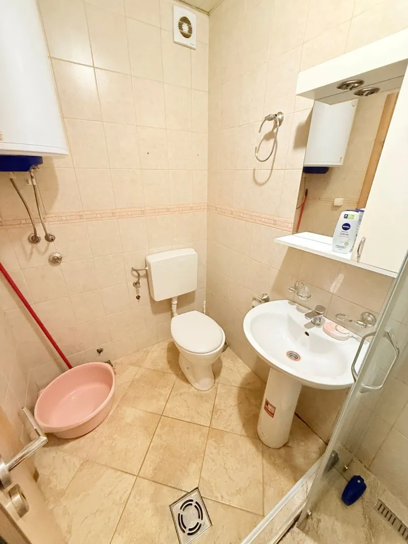 Small bathroom with tiles, washbasin, toilet, and shower cabin.