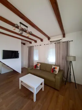 Dnevna soba sa kaučem, stočićem i drvenim gredama na plafonu. - image 14