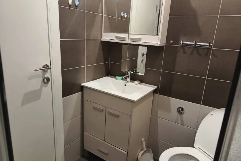 Small bathroom with a sink, cabinet, mirror, and toilet.