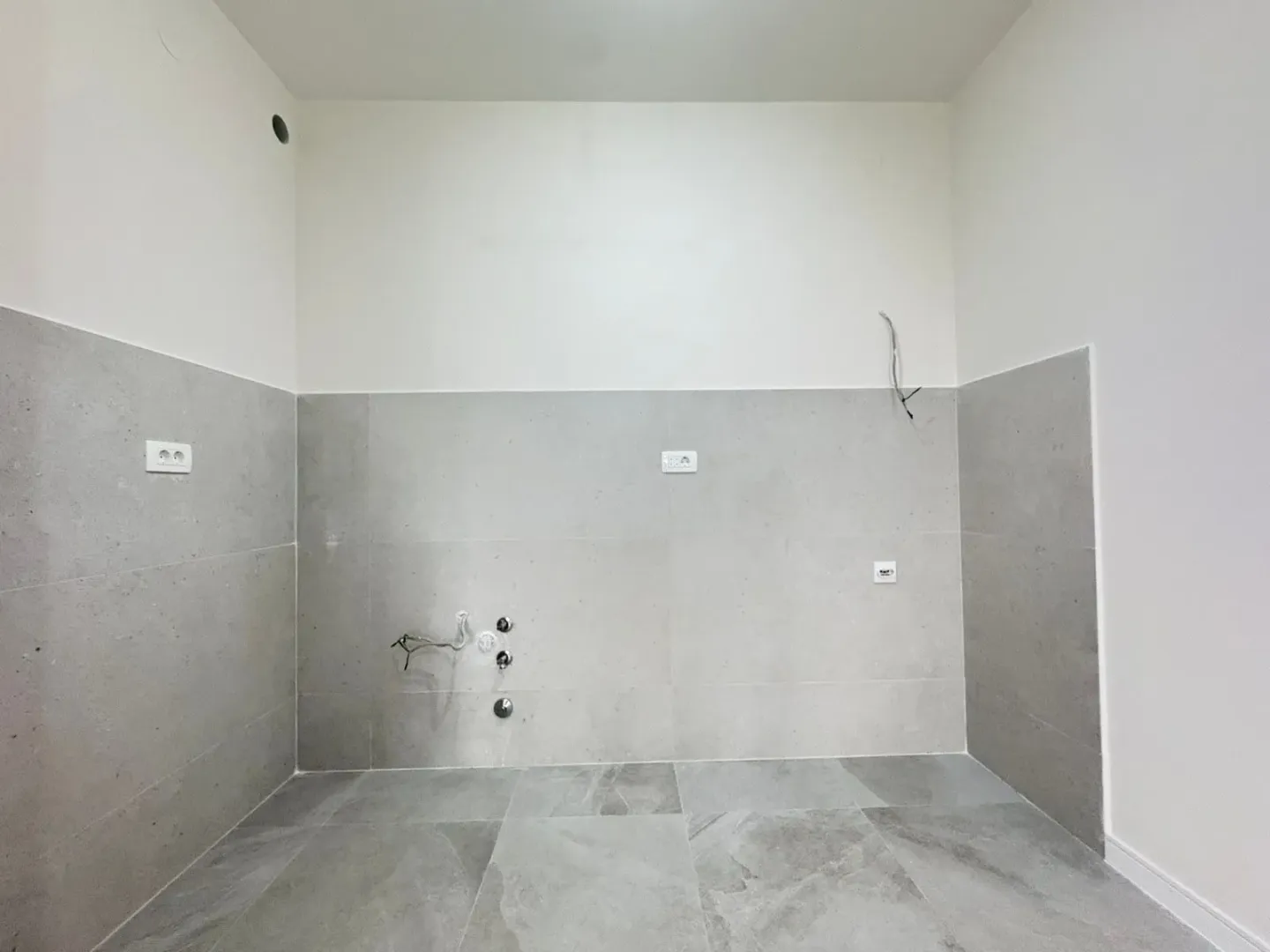 Empty space intended for a kitchen with installed tiles and connections.