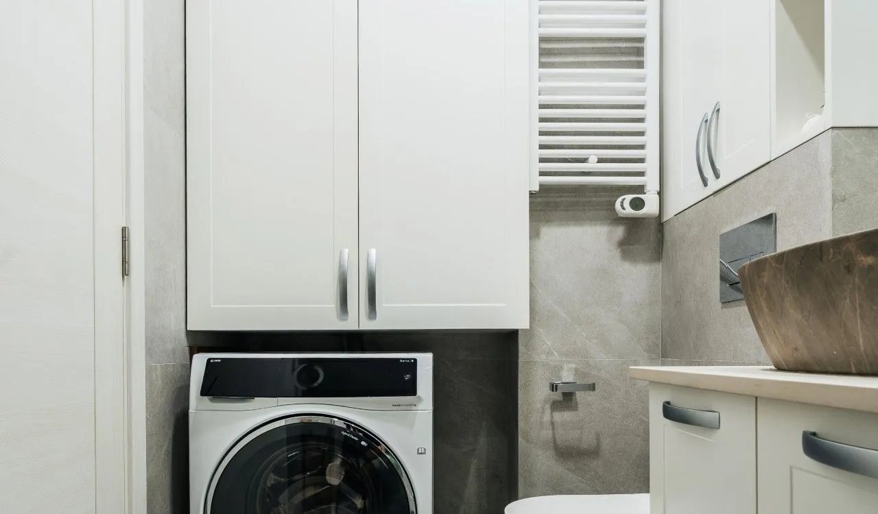 View of the bathroom with a washing machine and a cabinet.