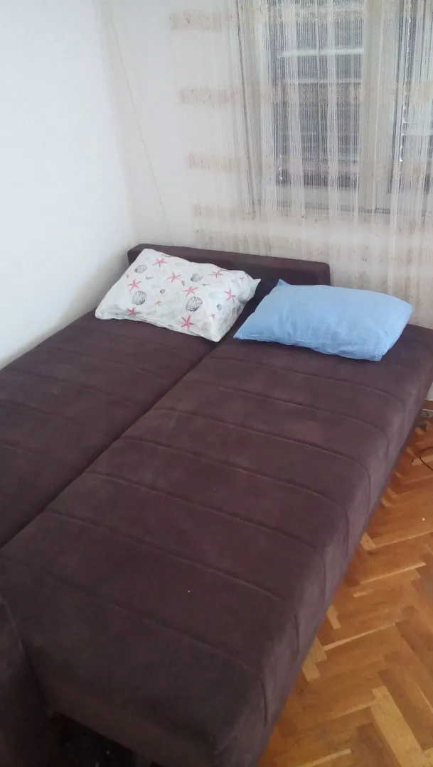 Spavaća soba sa bračnim krevetom i parketom na podu.