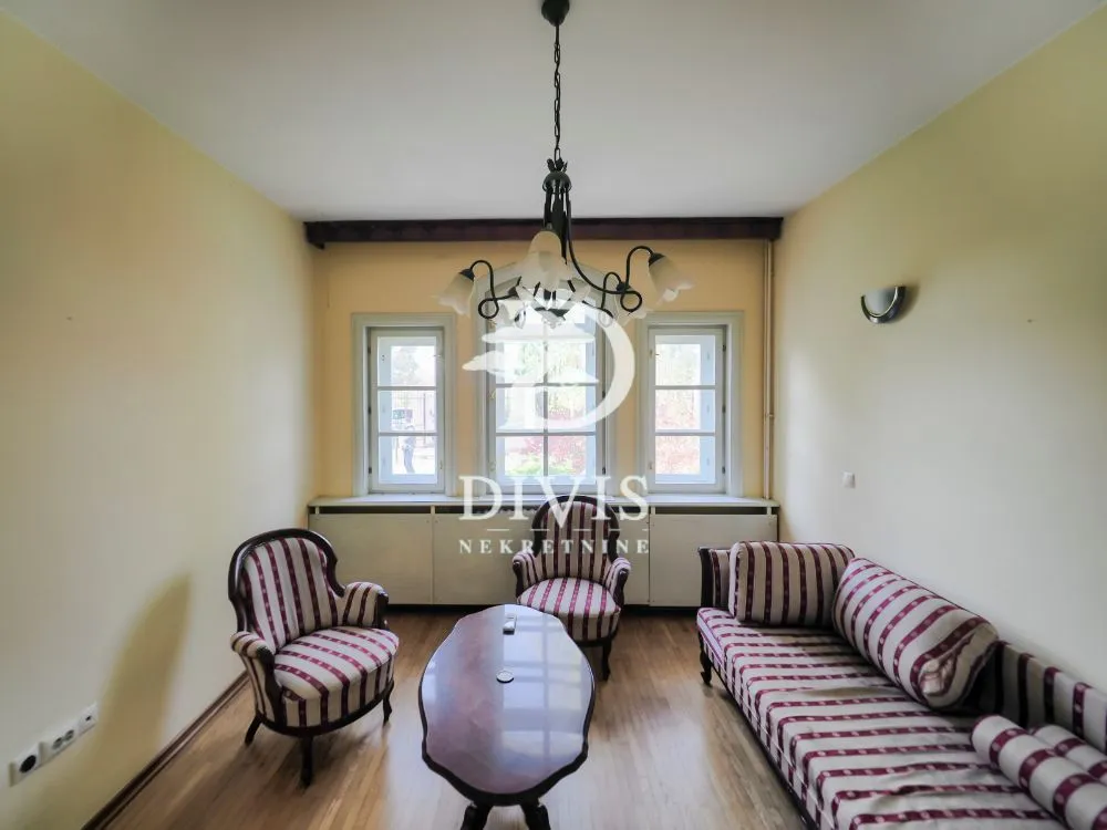Living room with seating furniture and three windows.