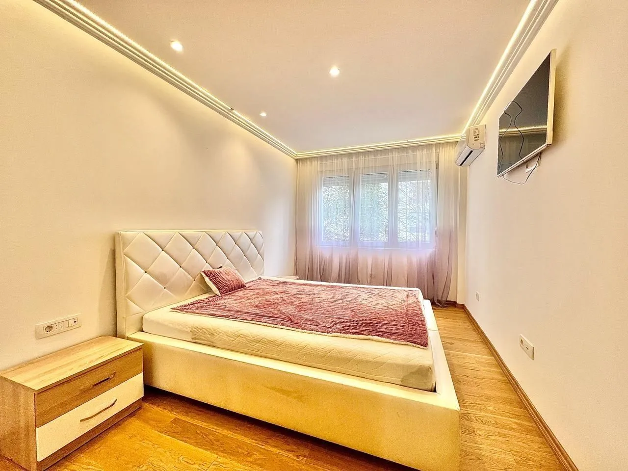Bright bedroom with a double bed and a wall-mounted TV.