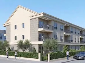 Spoljašnji izgled moderne stambene zgrade sa uređenim dvorištem.