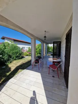 Natkrivena terasa sa stolom i stolicama i pogledom na dvorište. - image 7