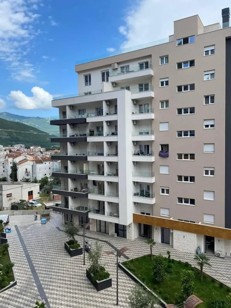 Eksterijer moderne stambene zgrade sa uređenim dvorištem.
