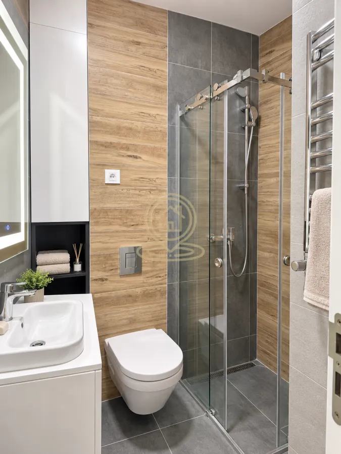 Moderno kupatilo sa tuš kabinom, umivaonikom i ugradnom wc šoljom.