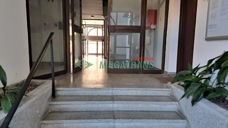 Ulaz u stambenu zgradu sa stepeništem i staklenim vratima.