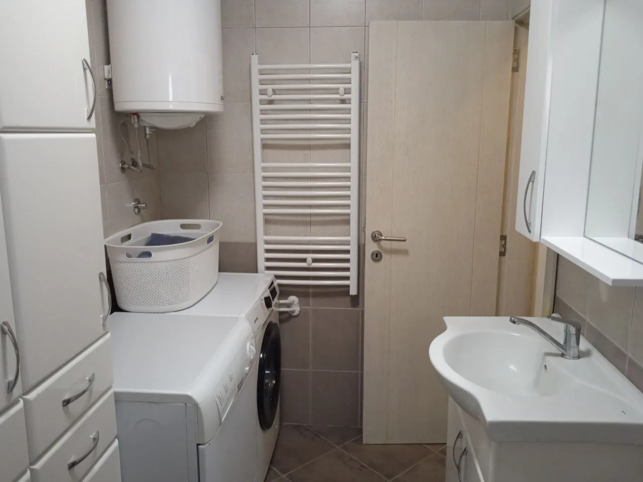 Manje kupatilo sa umivaonikom, veš mašinom i bojlerom.