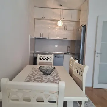 Dining area with a white table and chairs located next to the compact kitchen. - image 2