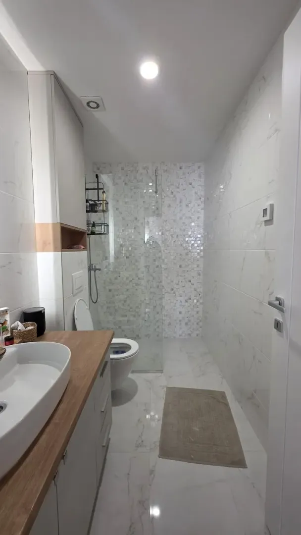 Moderne kupatilo sa tuš kabinom, umivaonikom i ugradnim toaletom.