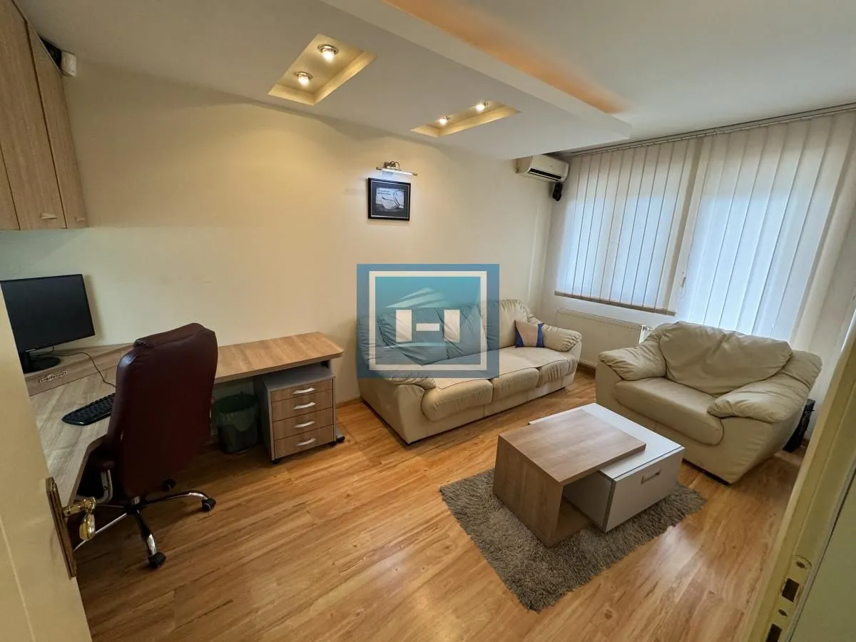 Living room with seating furniture, a desk, and a wooden floor.
