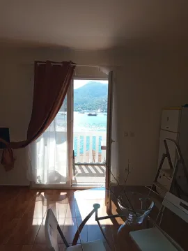 View from a bright room towards the sea and mountains through an open balcony door. - image 3