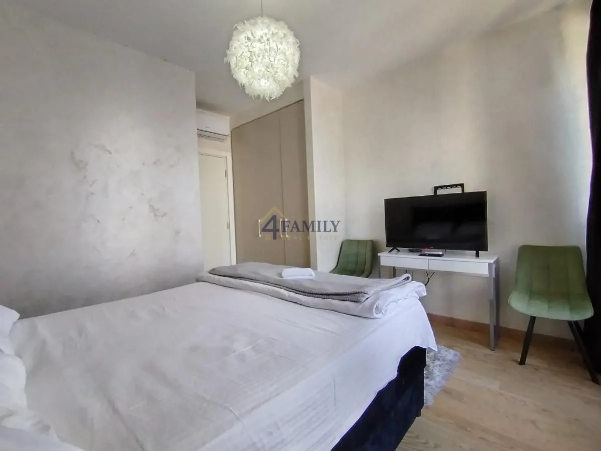 Furnished bedroom with a double bed, wardrobe, and a TV.