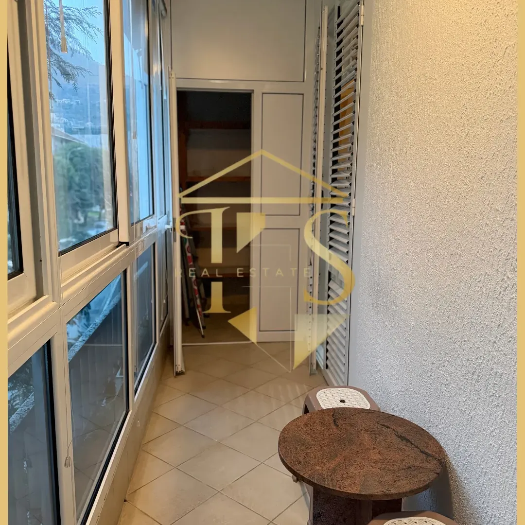 Zastakljena terasa sa malim stolom i stolicama.